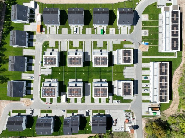 Dachinspektion Luftaufnahme einer modernen Wohnsiedlung mit Reihenhäusern und Grünflächen.