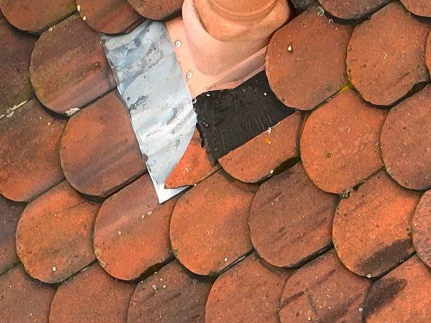 Schadensanalyse Ziegeldach mit einer fehlenden Fliese und einer metallischen Reparaturstelle.