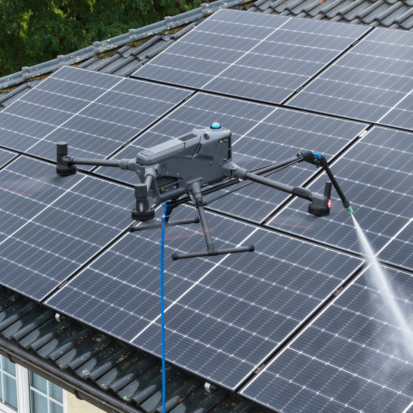 Drohne reinigt Solarpanels auf einem Dach mit Wasser.