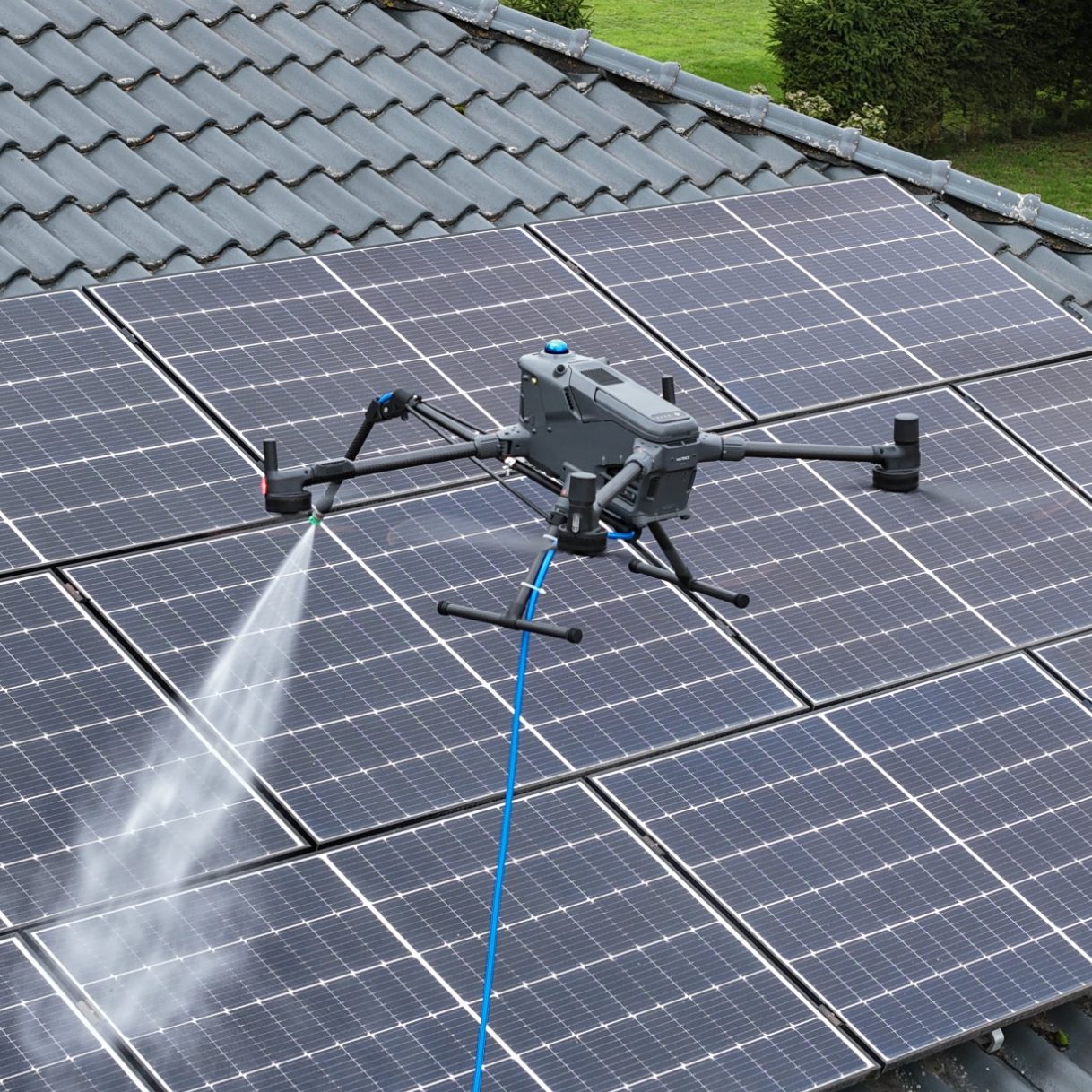 Ein Drohne sprüht Wasser über Solarpanels auf einem Dach.