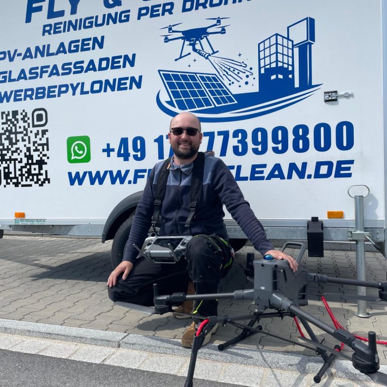 Drohne Mann sitzt neben Drohne und Ausrüstung vor einem Fahrzeug mit Unternehmensbeschriftung.