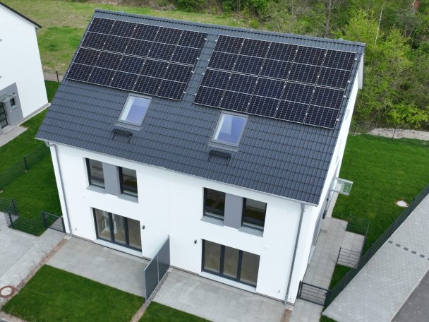 PV-Inspektion modernes Haus mit Solarpanelen auf dem Dach und grüner Rasenfläche.