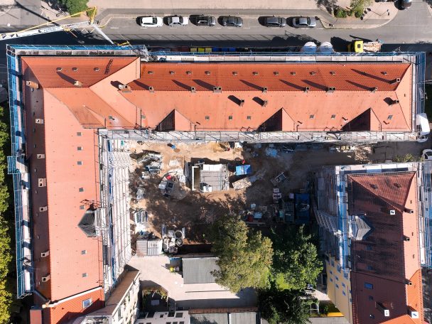 Baustelleninspektion Dachansicht eines Gebäudes mit roten Ziegeln und Baustelle im Innenhof.